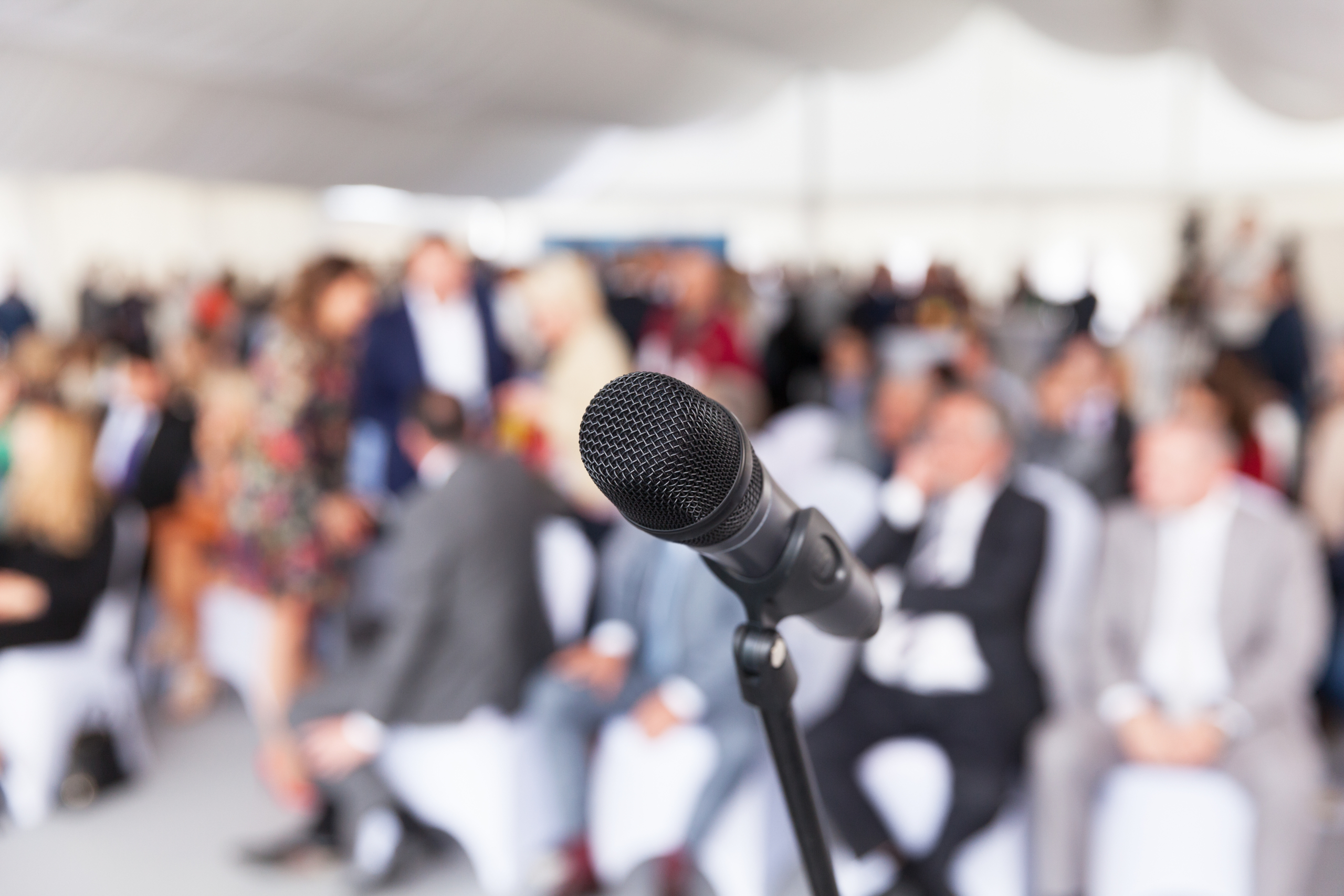 Microphone in focus against blurred audience. Participants at the business or professional conference.