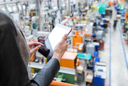 Person with ipad overlooking manufacturing facility