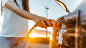 a woman's hand plugging in an electric vehicle
