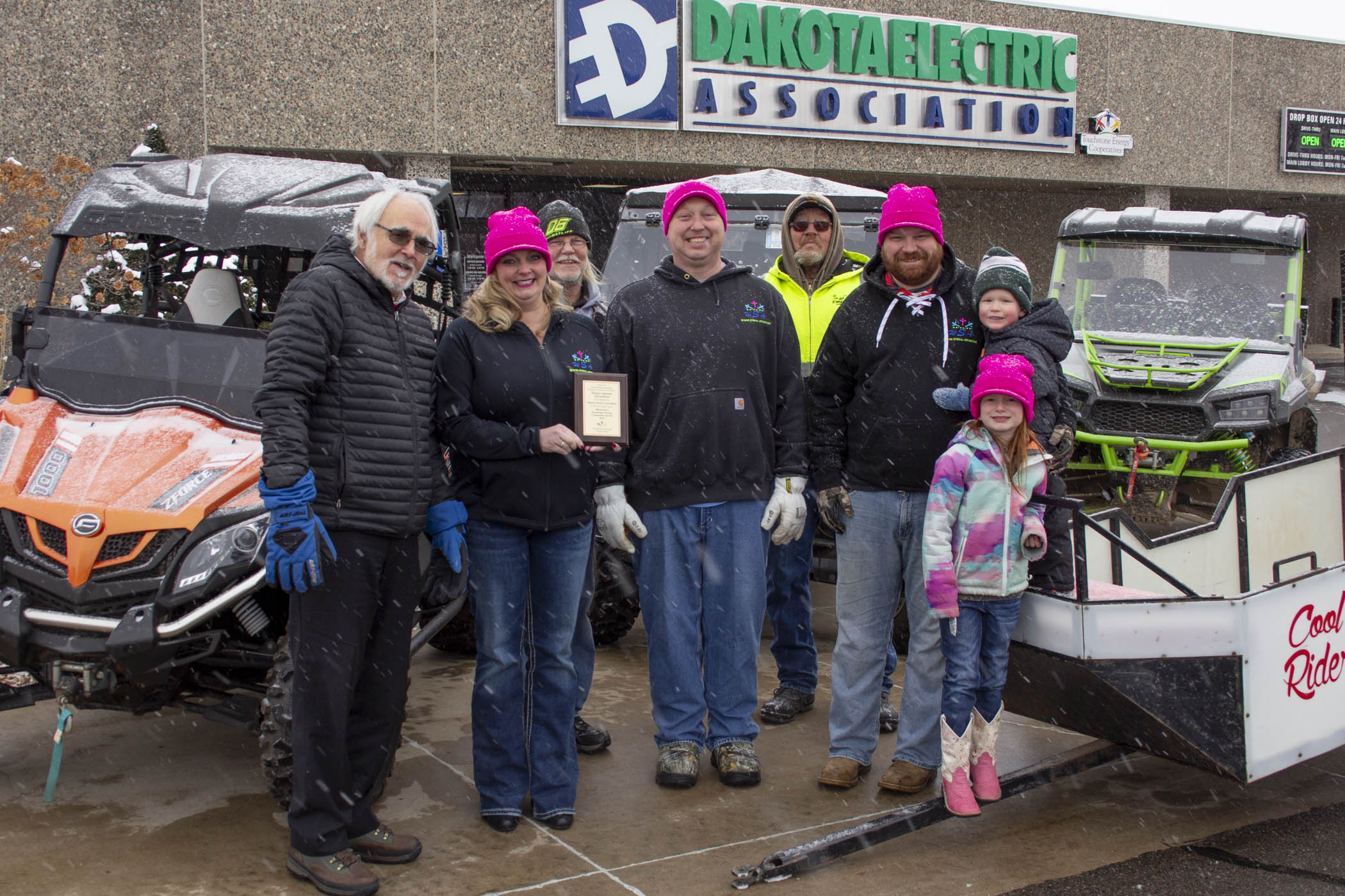 Winter Adventures group posing with UTVs outside of Dakota Electric